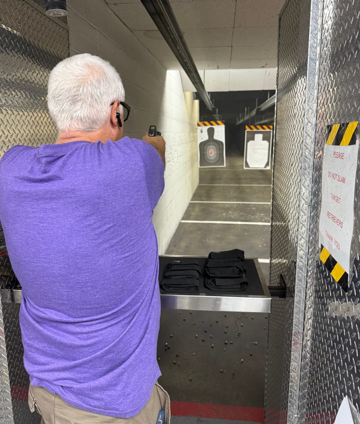 A shooter practicing handgun marksmanship in an indoor range lane